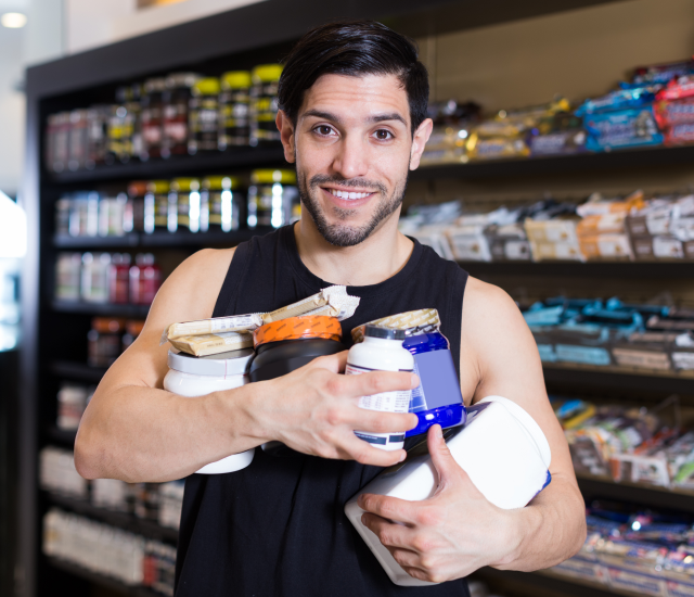 Man holding multiple supplement bottles